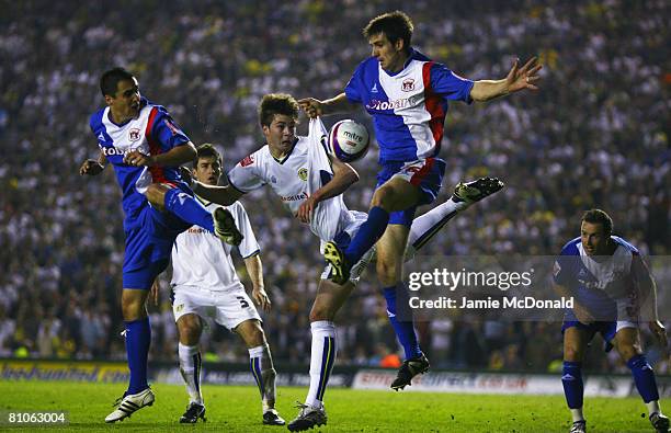 Paul Huntington of Leeds heads the ball between Scott Dobie and Evan Horwood of Carlisle during the League 1 Playoff Semi Final, 1st Leg match...