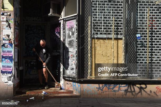 Man sweeps the entrance of a house after riots in Hamburg's Schanzenviertel district on July 8, 2017 in Hamburg, northern Germany, where leaders of...