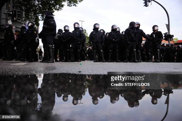 Riot police reflect in a puddle during protests in Hamburg's Schanzenviertel district on July 7, 2017 in Hamburg, northern Germany, where leaders of...