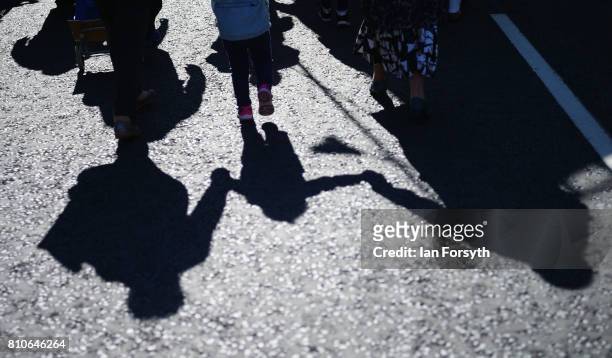 The shadow of a young girl is cast on the road as she marches with her parents through Durham city during the 133rd Durham Miners Gala on July 8,...
