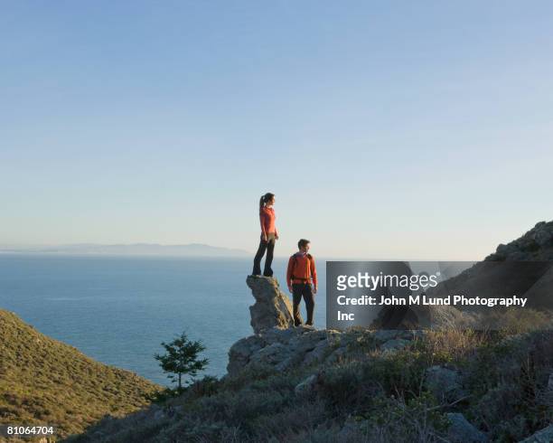 hispanic couple on cliff overlooking water - looking over cliff stock pictures, royalty-free photos & images