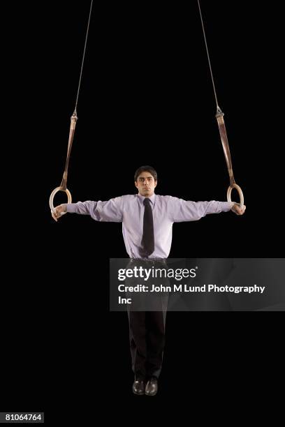 hispanic businessman performing on gymnastics rings - male gymnast stock pictures, royalty-free photos & images