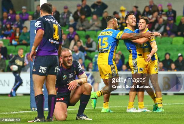 Mitchell Moses of the Eels is congratulated by his teammates after scoring a try as Nate Myles of the Storm looks on during the round 18 NRL match...