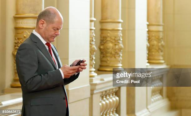 First Mayor of Hamburg Olaf Scholz looks at his smartphone as he arrives at the Hamburg Town Hall prior to the partner program of G20 summit on the...