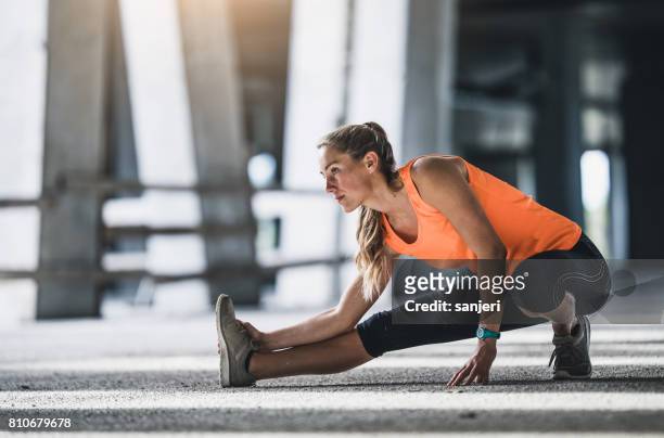 vrouwelijke atleet, die zich uitstrekt buiten - warm up exercise stockfoto's en -beelden