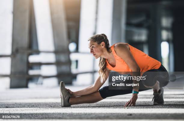 female athlete stretching outdoors - aquecimento físico imagens e fotografias de stock