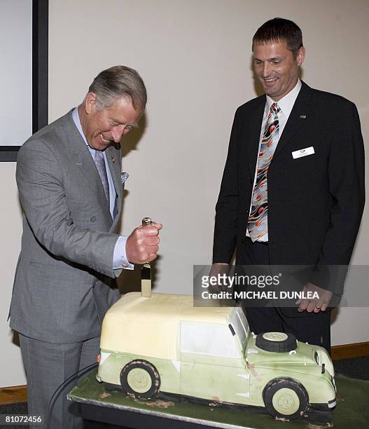 Britain's Prince Charles cuts a cake in the shape of a Land Land Rover as Land Rover Managing Director Phil Popham looks on at the Land Rover factory...