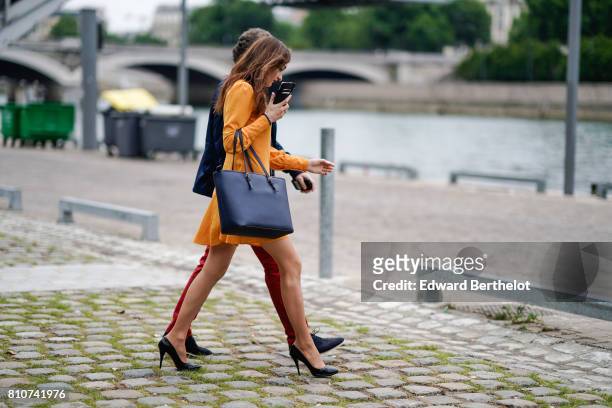 Guest wears an orange dress, and black bag, during Paris Fashion Week - Haute Couture Fall/Winter 2017-2018, on July 2, 2017 in Paris, France.