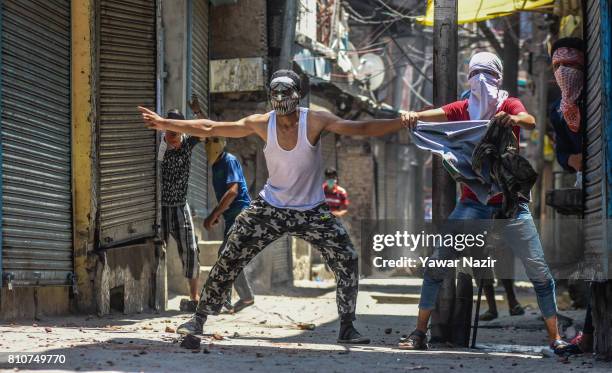 Masked Kashmiri Muslim protesters taunts Indian government forces during a protest after they defied curfew, on the the first death anniversary of...