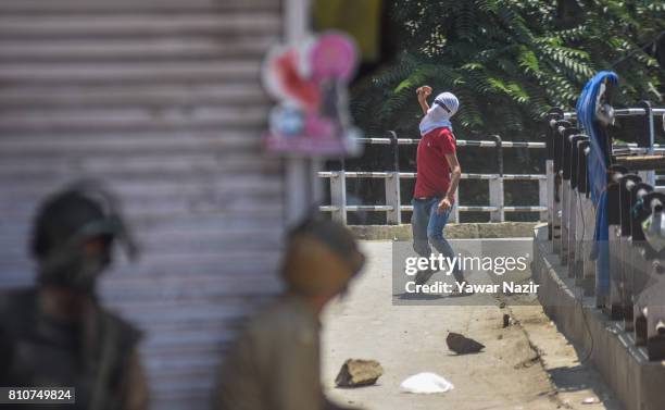 Kashmiri Muslim protester throws a stone at Indian government forces during a protest after they defied curfew, on the the first death anniversary of...