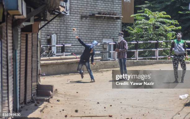 Kashmiri Muslim protester throws a stone at Indian government forces during a protest after they defied curfew, on the the first death anniversary of...