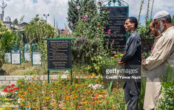 Kashmiri Muslims offer prayers at the martyrs graveyard during a curfew, on the the first death anniversary of Burhan Wani a young rebel commander,...