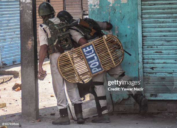 Indian paramilitary troopers look towards Kashmiri Muslim protester throwing stones at them during a protest after Kashmiri Muslims defied curfew, on...