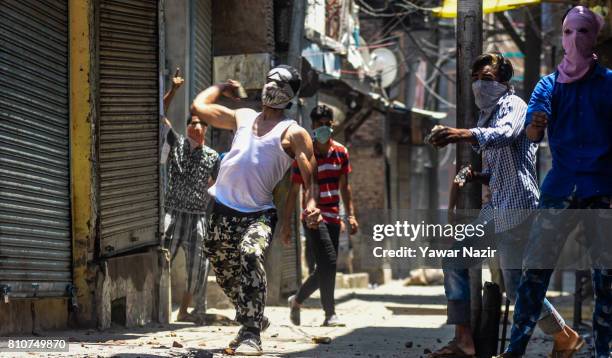 Masked Kashmiri Muslim protester throws a stone at Indian government forces during a protest after they defied curfew, on the the first death...