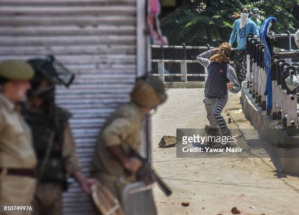 Kashmiri Muslim protester throws a stone at Indian government forces during a protest after they defied curfew, on the the first death anniversary of...