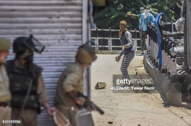 Kashmiri Muslim protester aims his stone at Indian government forces during a protest after they defied curfew, on the the first death anniversary of...