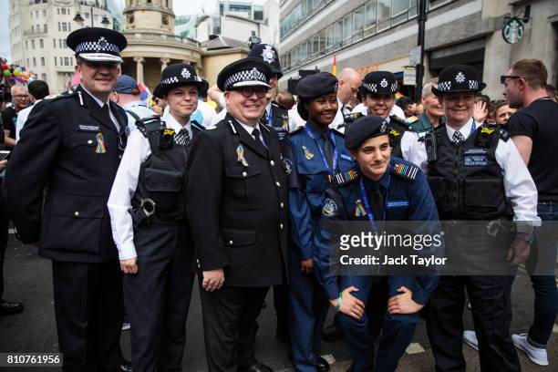 Police officers and police cadets wearing rainbow ribbons and epaulettes pose for a photograph at the Pride in London Festival on July 8, 2017 in...