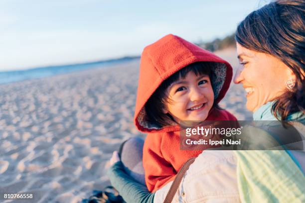 mother and little girl having intimate moment on winter beach - australia winter stock-fotos und bilder