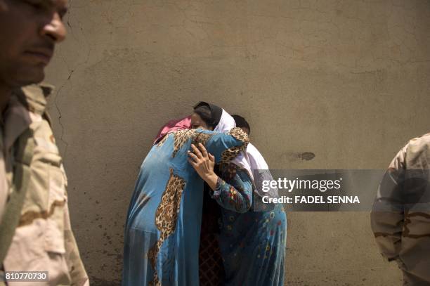 Iraqi women, who fled the fighting between government forces and Islamic State group jihadists in the Old City of Mosul, cry as they stand in the...