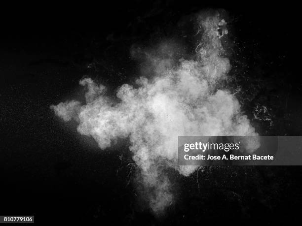 forms and textures of an explosion of a powder of color white on a black background - condensación fotografías e imágenes de stock