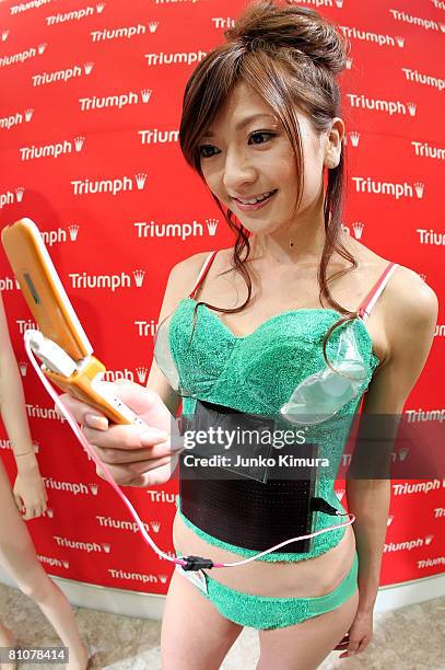 Mobile phone is charged by the lingerie maker Triumph's new environment-friendly "Photovoltaic-Powered Bra" at Tokyo Ryutsu Center on May 14, 2008 in...