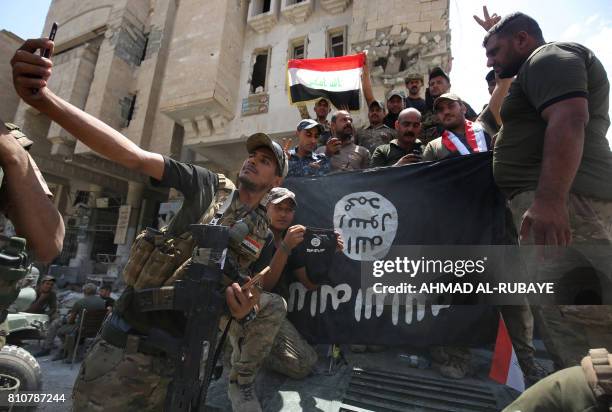 Members of the Iraqi interior ministry forces pose for a picture with an upside down Islamic State group flag in the Old City of Mosul on July 8 as...