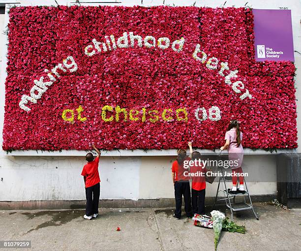 Sidal Durna, aged nice, is helped by her friends as she puts the finishing touches to the UK's first live flower billboard in Hackney on May 14, 2008...