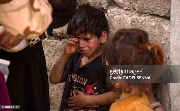 Iraqi children, who fled the fighting between government forces and Islamic State group jihadists in the Old City of Mosul, react as they stand by a...