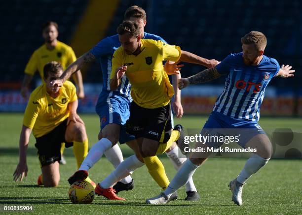 Scott Pittman of Livingston is challenged by Kirk Broadfoot and Alan Power of Kilmarnock during the pre season friendly between Kilmarnock and...