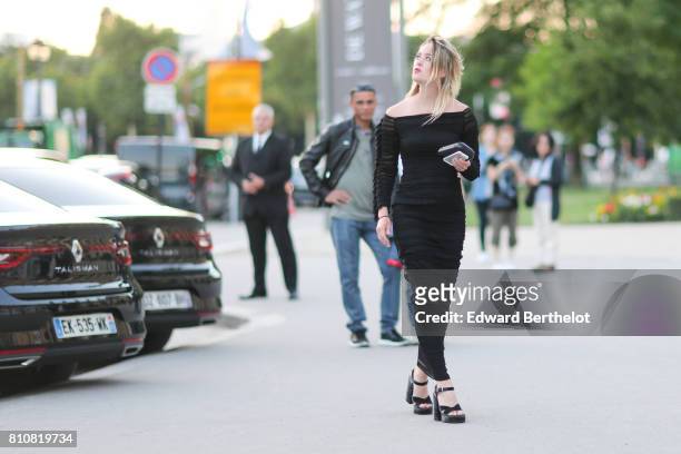 Guest wears an off-shoulder balck top, black pants, black shoes, outside the amfAR dinner at Petit Palais, during Paris Fashion Week - Haute Couture...