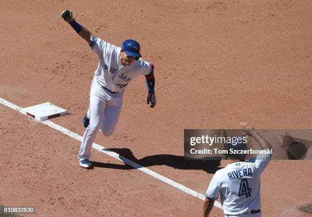 Troy Tulowitzki of the Toronto Blue Jays is congratulated by third base coach Luis Rivera as he circles the bases after hitting a three-run home run...