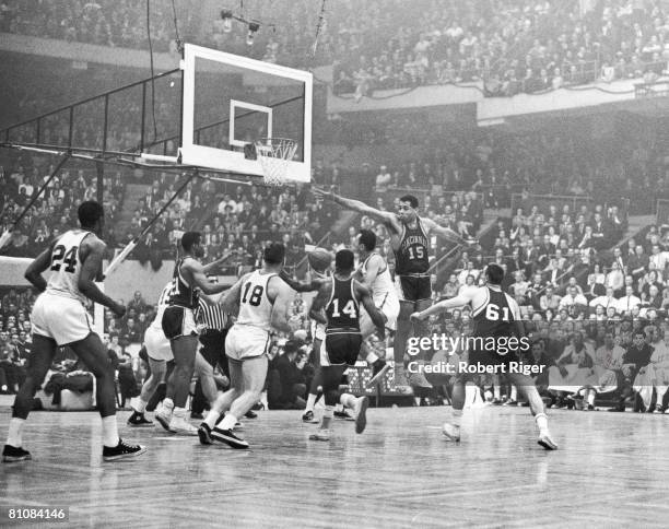 American baketball player Wayne Embry of the Cincinnati Royals leaps into the air and stretches out a hand to block a shot by Bob Cousy of the Boston...