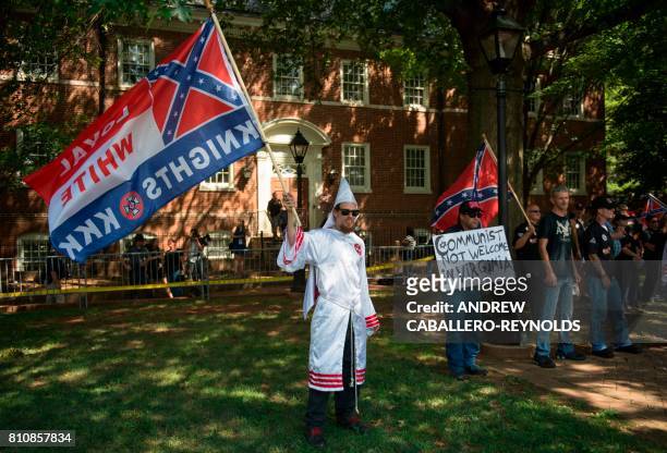 Members of the Ku Klux Klan wave flags as they hold a rally in Charlottesville, Virginia on July 8, 2017 to protest the planned removal of a statue...