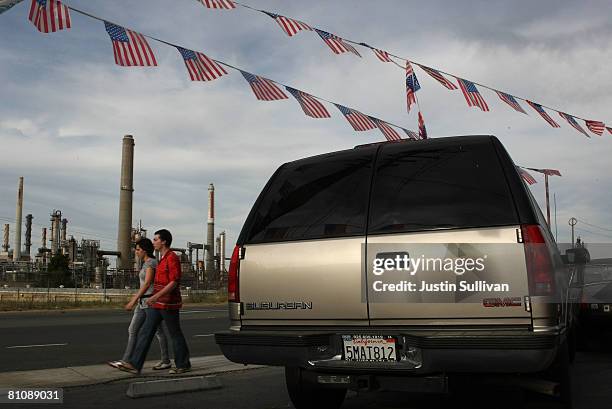 Pedestrians walk by a Chevrolet Suburban that is on display at a used car lot across from a Shell refinery May 14, 2008 in Martinez, California. The...