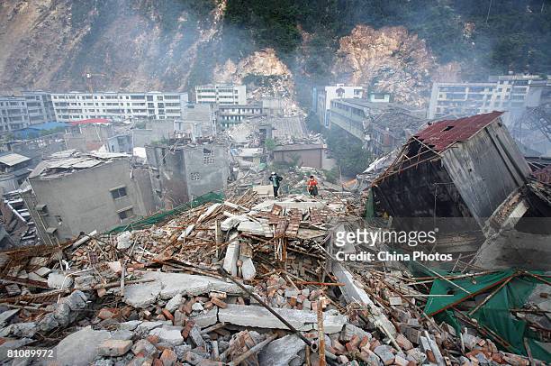 Earthquake survivors walk on the debris of collapsed houses, in search of relatives on May 14, 2008 in Beichuan County, Sichuan Province, China. A...