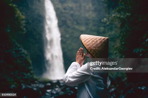 religiöse asiatische frauen beten durch den regenwald-wasserfall - balinesische kultur stock-fotos und bilder