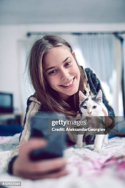 cute smiling young girl taking selfie with cat - cat selfie stock pictures, royalty-free photos & images