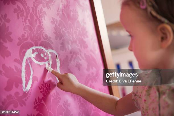 girl finger painting a rabbit shape onto pink wallpaper - 4 girls finger painting bildbanksfoton och bilder