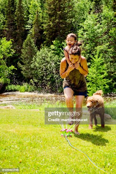 tausendjährige mutter springkling wasser mit tochter genießen. - baby lachen natur stock-fotos und bilder