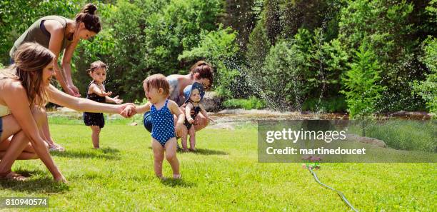 millennials mères bénéficiant springkling eau avec filles de bébé. - family garden play area photos et images de collection