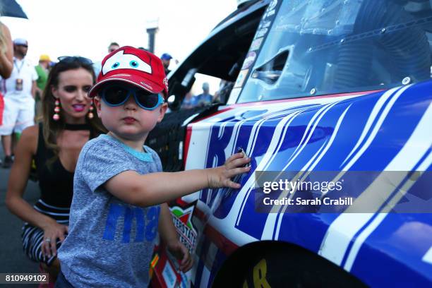 Brexton Busch, son of Kyle Busch, driver of the Snickers Toyota, places tape on the car before the Monster Energy NASCAR Cup Series Quaker State 400...