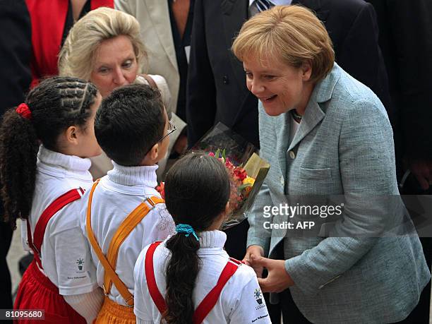 German Chancellor Angela Merkel greets children during a visit to the Volkswagen plant, on May 15 in Sao Bernardo do Campo, southern Sao Paulo,...