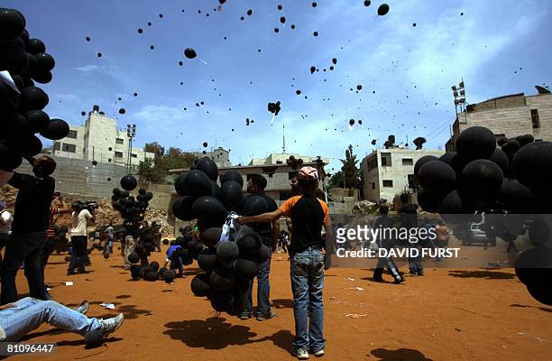 Palestinians release black balloons during a ceremony marking the "Nakba" at the Qalandia refugee camp near the West Bank city of Ramallah on May 15,...