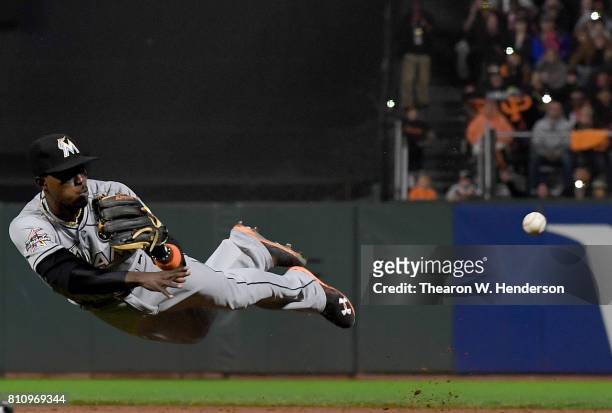Dee Gordon of the Miami Marlins dives and throws to first base throwing out Brandon Crawford of the San Francisco Giants on the play in the bottom of...