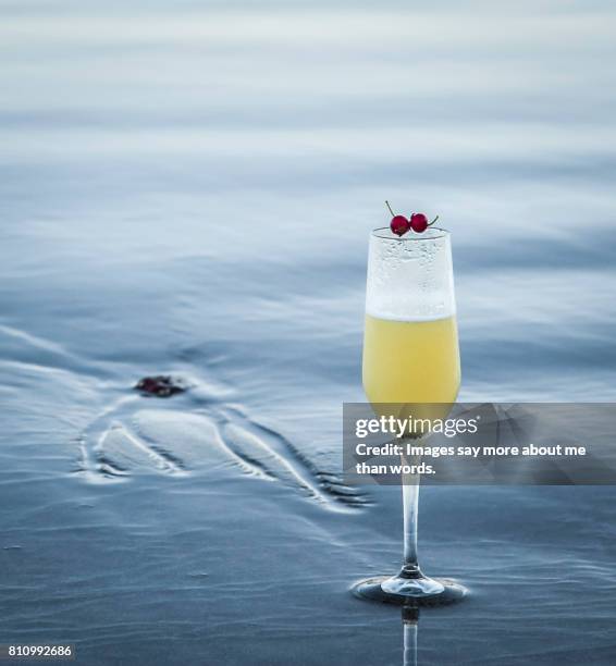 close up of drink on beach sand surrounded by waves. - pisco sour imagens e fotografias de stock