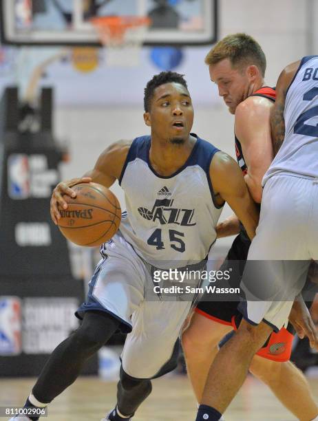 Donovan Mitchell of the Utah Jazz drives against Jake Layman of the Portland Trail Blazers during the 2017 Summer League at the Cox Pavilion on July...