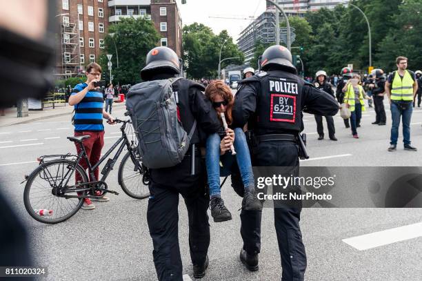 Policemen carry a woman of the street while she is playing a flute, in Hamburg, Germany, on July 7, 2017. Activists tried to enter the red security...