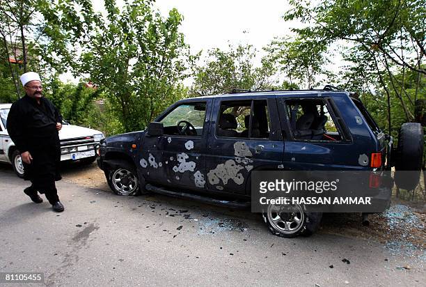 Lebanese Druze cleric walks past a bullet-riddled car in the Druze village of Baysur in Mount Lebanon on May 16, 2008 one day after roadblocks were...