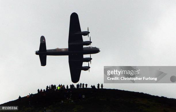 Spectators on a hill look on as a Lancaster bomber flies over Ladybower reservoir in the Derbyshire Peak District to mark the 65th anniversary of the...
