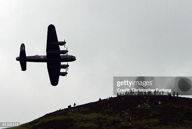 Spectators on a hill look on as a Lancaster bomber flies over Ladybower reservoir in the Derbyshire Peak District to mark the 65th anniversary of the...